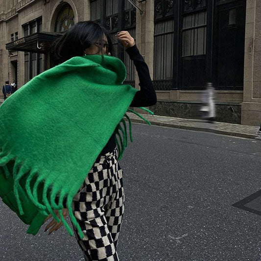 Woman wearing luxury green cashmere scarf with fringe on city street in stylish outfit